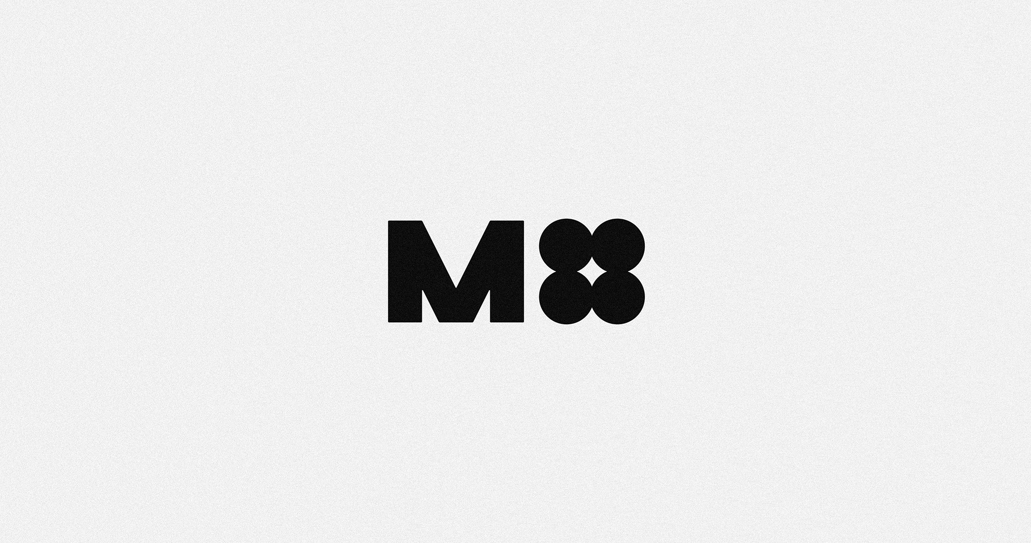 The M4 Music logotype. It features a bold, industrial, uppercase ‘M’, and 4 circles grouped together to represent the number ‘four’. Black logotype over white background.