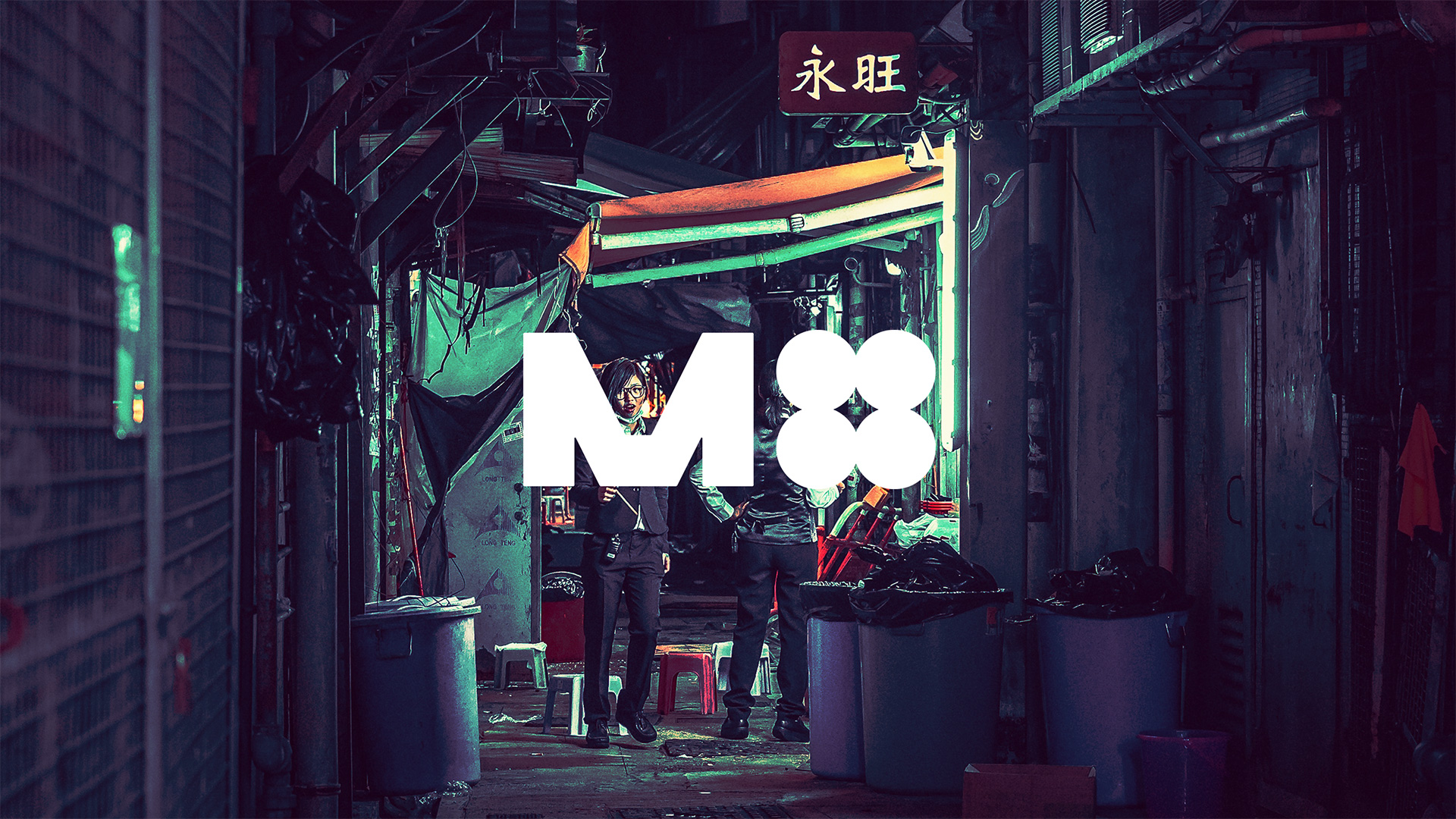 An industrial, symbol-based logo featuring a mechanical-feeling uppercase ‘M’, and four circles joined together to represent the number ‘four’; laid over a photograph featuring two people standing in an alleyway.