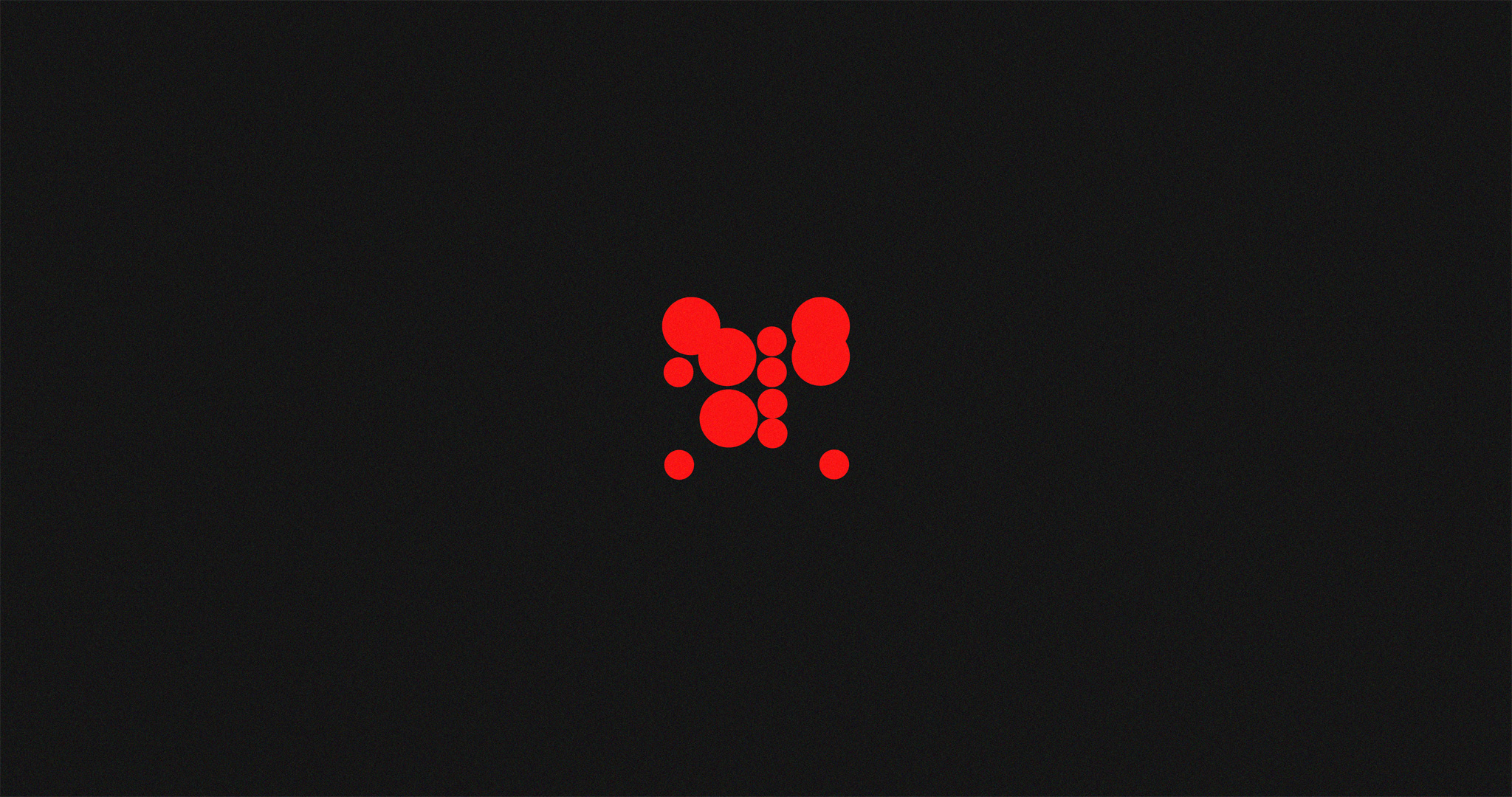 Proportionally-sized red circles arranged in a grid-like manner, covering a square area. Silhouette for a logotype which appears later in this article.